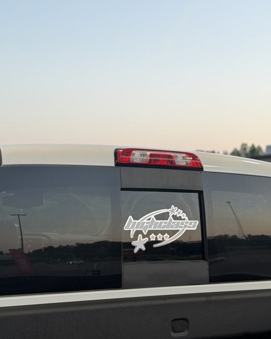 Club logo decal with stars on the rear sliding window of a white pickup at sunset